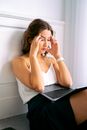femme se tenant la tete devant un ordinateur sur ses genoux, pour illustrer les pertes de mots au travail après 45 ans